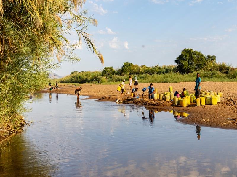 People were gathering water at the river by digging in the sand